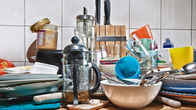 A pile of various kitchen utensils and dishes on a cupboard surface
