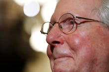 A closeup of Mitch McConnell where he is slightly smiling and looking ahead.