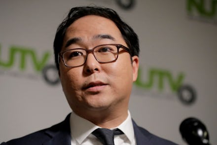 Andy Kim in a grey suit, white shirt, and a black tie being interviewed