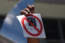 A hand holding a paper with a no Uber sign