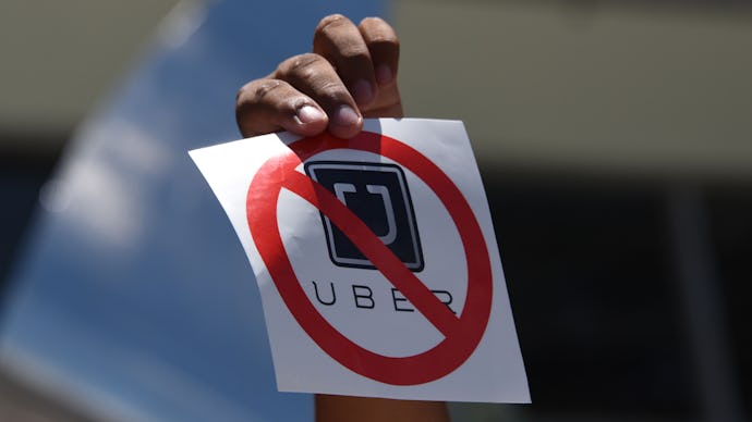 A hand holding a paper with a no Uber sign