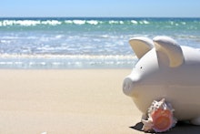 A piggy bank at the beach next to a conch