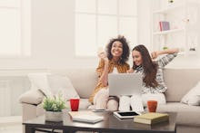 Two girls sitting in a living room and planning a travel trip