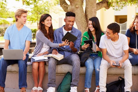 Group of students listening to their online school lectures in a park