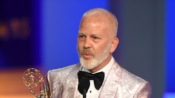 Ryan Murphy holding his Emmy award trophy
