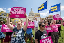 Woman and men protesting against abortion laws, holding their signs, most of them with an open mouth...
