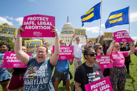 Woman and men protesting against abortion laws, holding their signs, most of them with an open mouth...