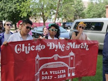 People marching holding a "Chicago Dyke March" sign in red with white writing