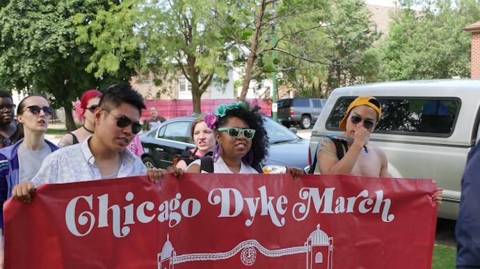 People marching holding a "Chicago Dyke March" sign in red with white writing
