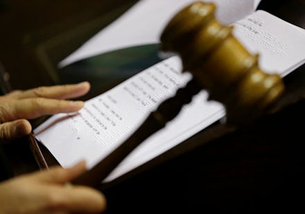 A judge reading a paper with rules and holding a judge hammer
