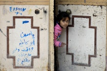 A girl from Syria looking through opening a door