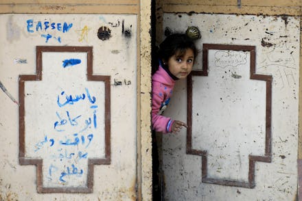 A girl from Syria looking through opening a door