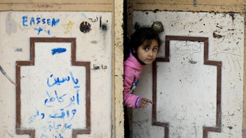 A girl from Syria looking through opening a door