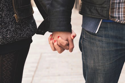 Two celibate partners holding hands while walking down a street