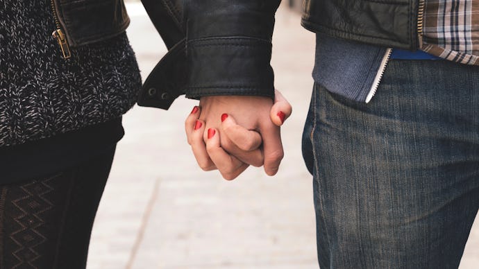 Two celibate partners holding hands while walking down a street