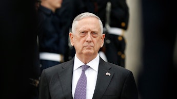 James Mattis standing in a formal suit with a purple tie