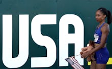 Rio Olympic Athlete Allyson Felix standing next to a large USA poster, and holding a small American ...