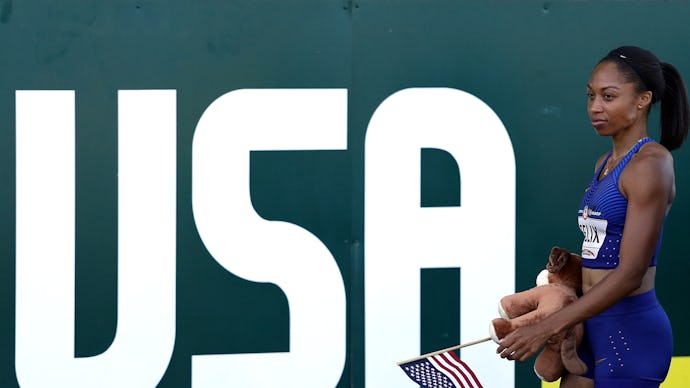 Rio Olympic Athlete Allyson Felix standing next to a large USA poster, and holding a small American ...