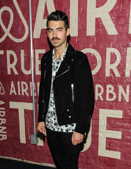 Joe Jonas posing for a photo in a black jacket