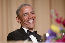 Barack Obama in a black suit, white shirt, and a black bow tie smiling