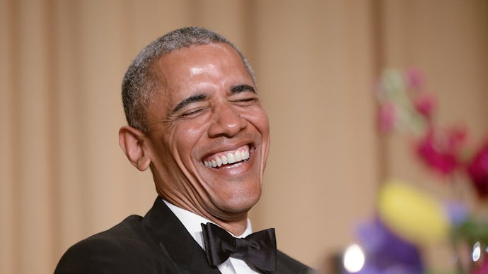 Barack Obama in a black suit, white shirt, and a black bow tie smiling