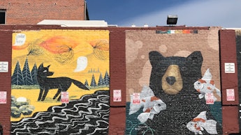 Big graffiti drawings of fox and bear on a brick wall