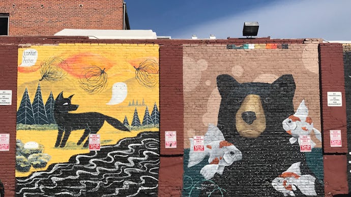 Big graffiti drawings of fox and bear on a brick wall