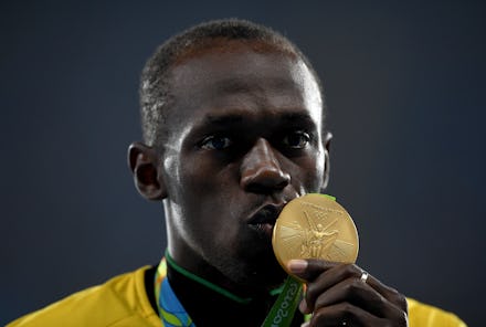 A close up of Usain bolt, kissing his golden medal
