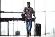 A man on the airport scrolling through his travel app