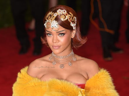 Rihanna wearing a furry yellow outfit and an extravagant head band at a red carpet event