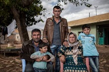 A Syrian family of five sitting on plastic chairs outside