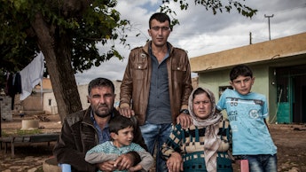 A Syrian family of five sitting on plastic chairs outside