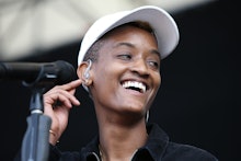 Syd Tha Kyd performing on stage with a white cap and a black T-shirt