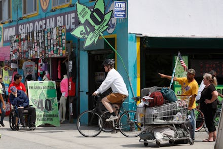 A man riding a bike next to a marijuana shop