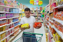 A man at the supermarket deciding between a generic item and one with a famous brand name 