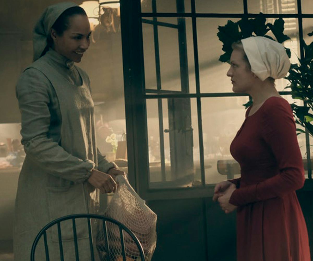 Two woman dressed as maids in white and red clothes acting in a scene from the series Handmaid's Tal...