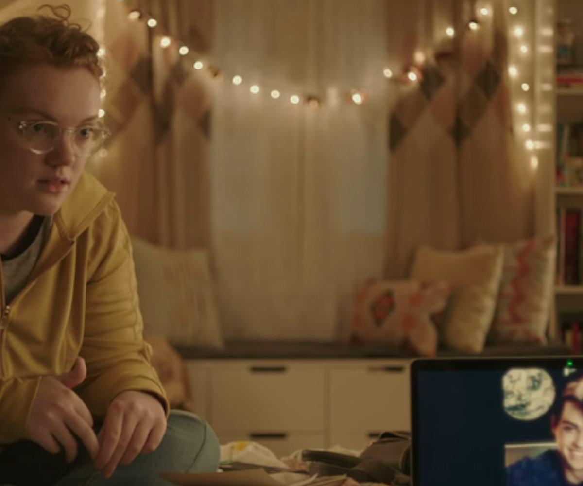 Barb from Stranger Things sitting on a bed and looking at a computer