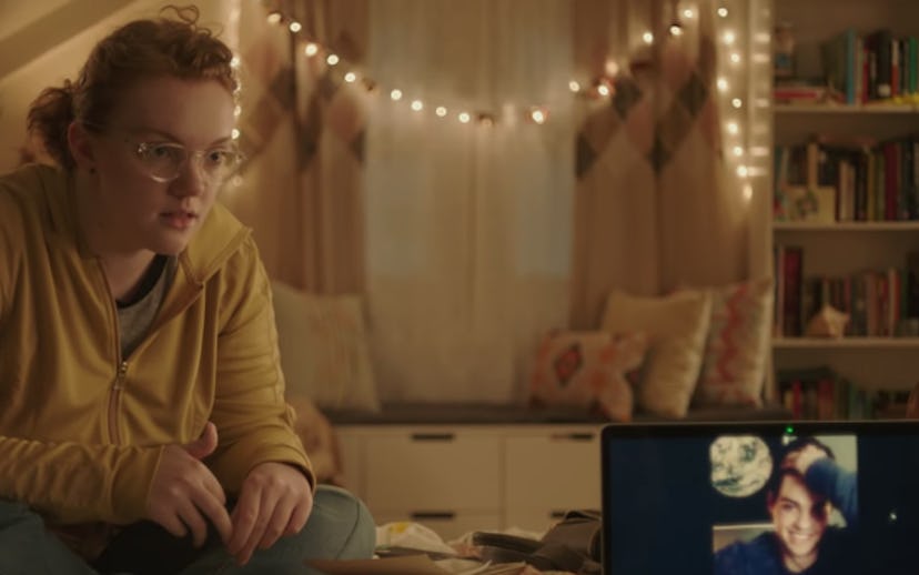 Barb from Stranger Things sitting on a bed and looking at a computer
