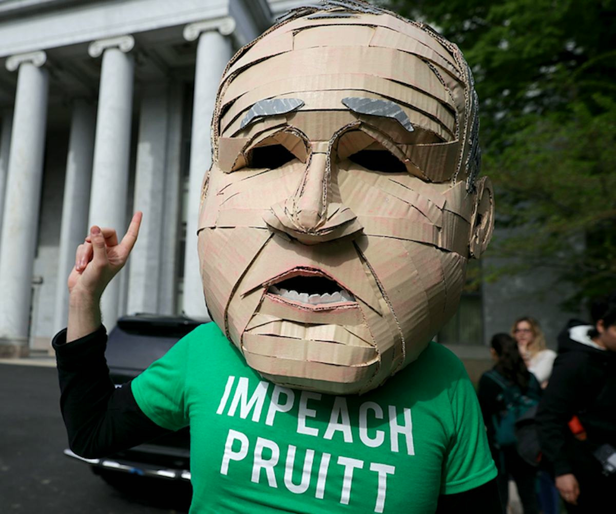 Scott Pruitt's oversized head mascot stands with his finger in the air and wears a green t-shirt tha...