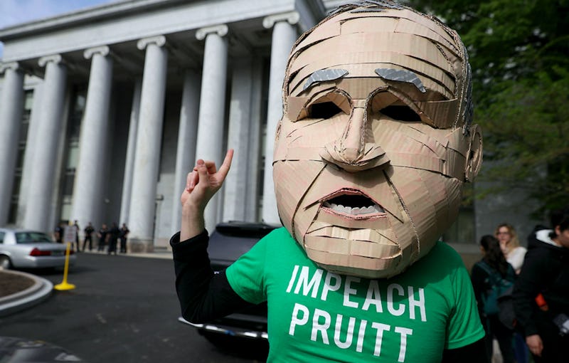 Scott Pruitt's oversized head mascot stands with his finger in the air and wears a green t-shirt tha...