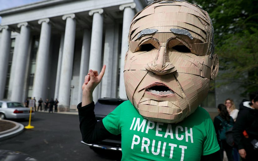 Scott Pruitt's oversized head mascot stands with his finger in the air and wears a green t-shirt tha...