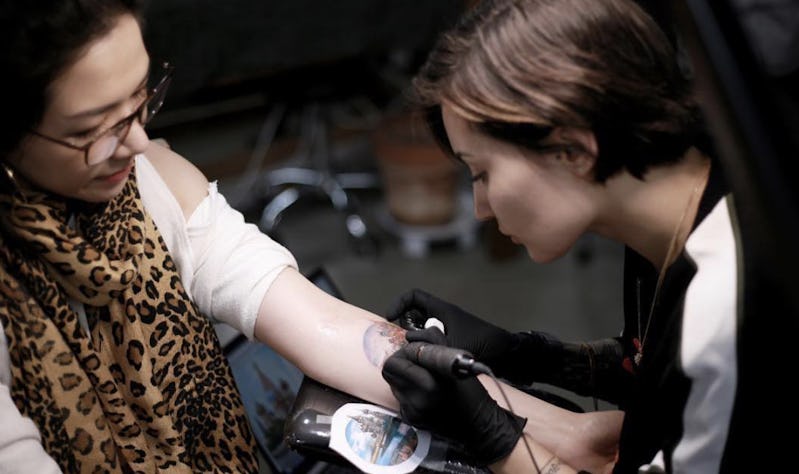 Woman tattoo artist tattooing another woman.