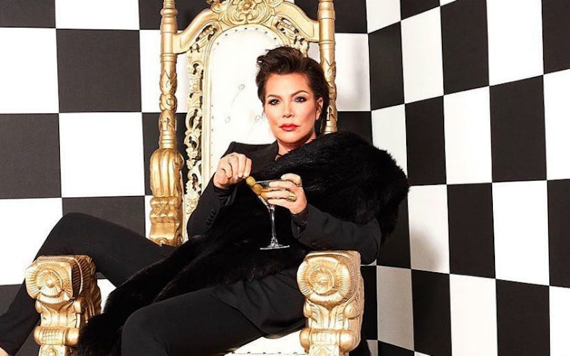 Kris Jenner in all black, sitting on a throne in a black and white checkered room