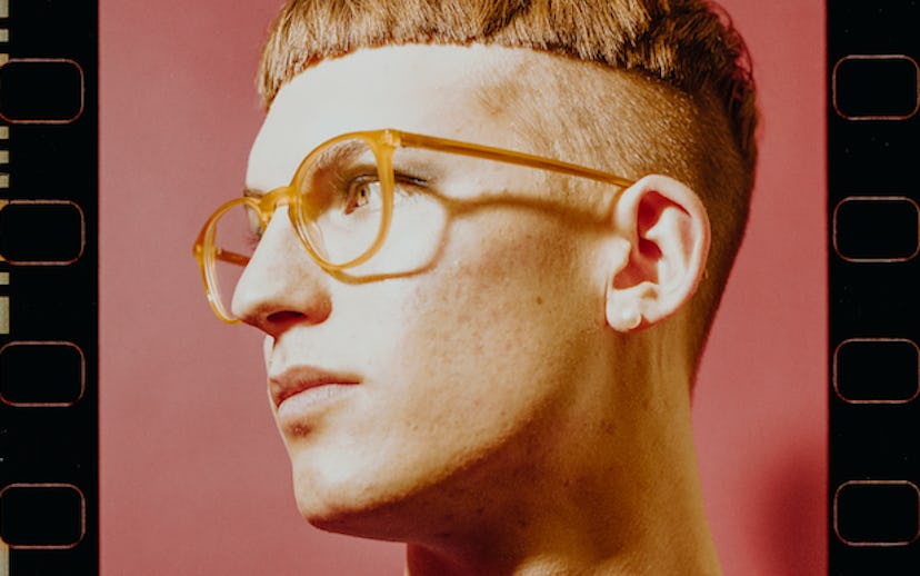Gus Dapperton with a bowl cut hairstyle and orange glasses