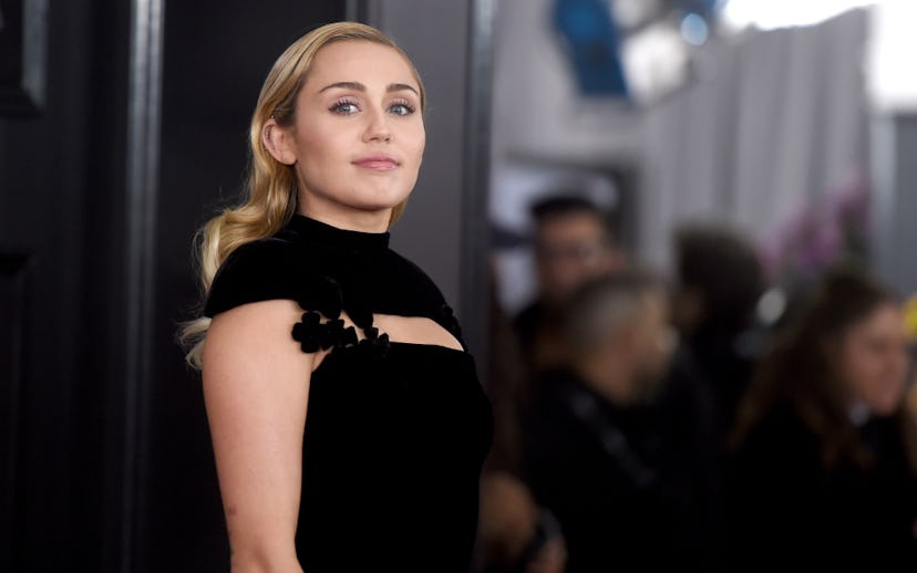 Miley Cyrus posing in a black dress