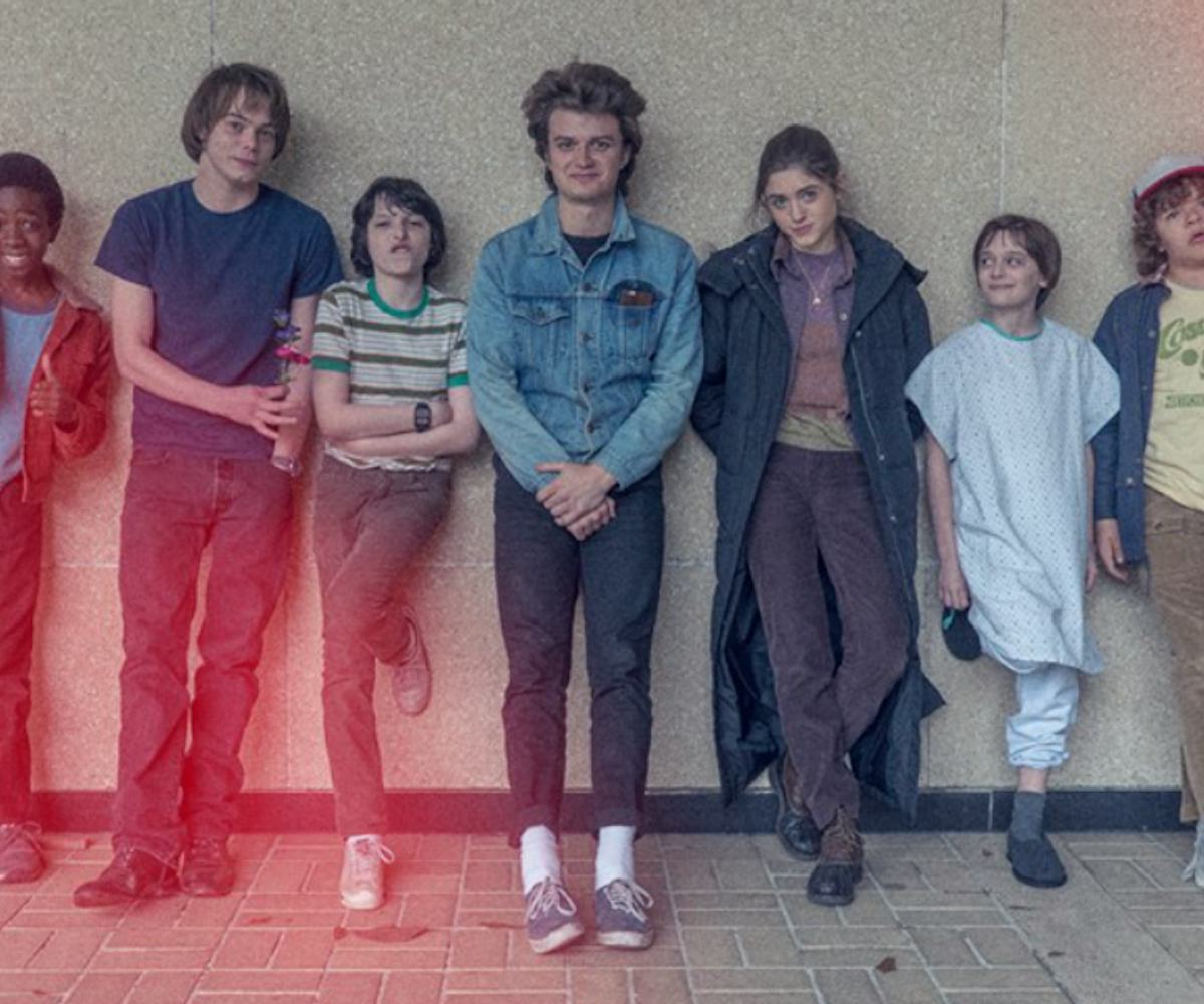 The cast of Stranger Things, two teenagers and two children, a boy and a girl, leaning against the w...
