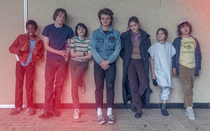 The cast of Stranger Things, two teenagers and two children, a boy and a girl, leaning against the w...