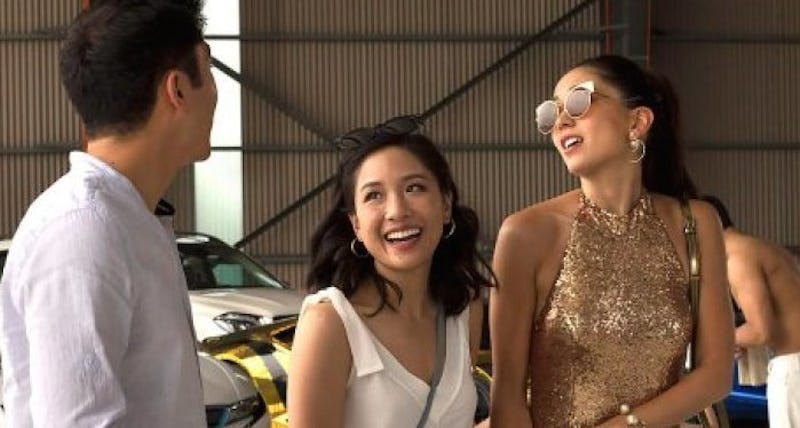 A shot of Henry Golding, Constance Wu, and Jin Lusi in the movie Crazy Rich Asians talking and smili...