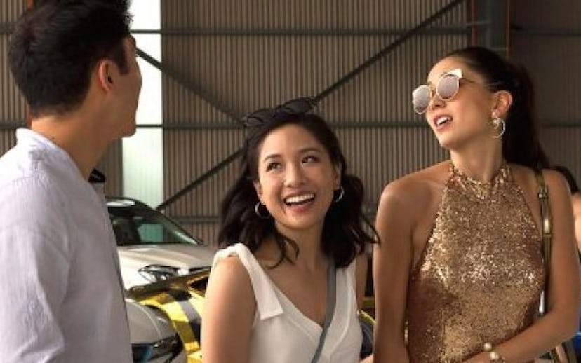 A shot of Henry Golding, Constance Wu, and Jin Lusi in the movie Crazy Rich Asians talking and smili...