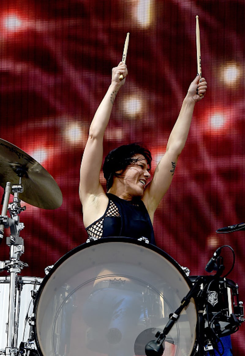 A female drummer performing on stage with her hands up in the air